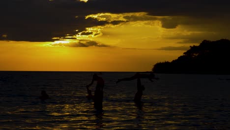 Silhouettes-of-family-playing-in-the-sea-with-the-sun-setting-in-the-background
