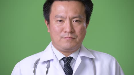 성숙한 일본인 남성, 초록색 배경의 의사