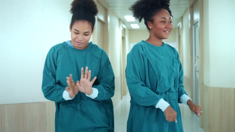 happy african american nurses and assistants dances while walk through the corridors of hospital. medical personnel having enjoy.