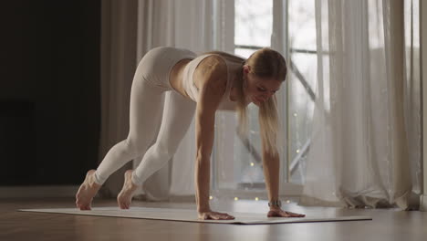 a young woman in white sportswear is stretching with a large hall with large windows in a slow-motion scheme the sun's rays shine through the window. healthy lifestyle healthy morning