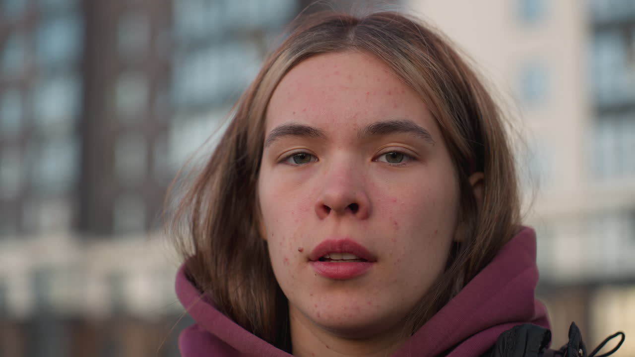 Portrait of fair skinned woman exhaling relief with closed eyes on urban sports court backdrop, subtle sunset glow on modern buildings, calm expression capturing breath release after workout session