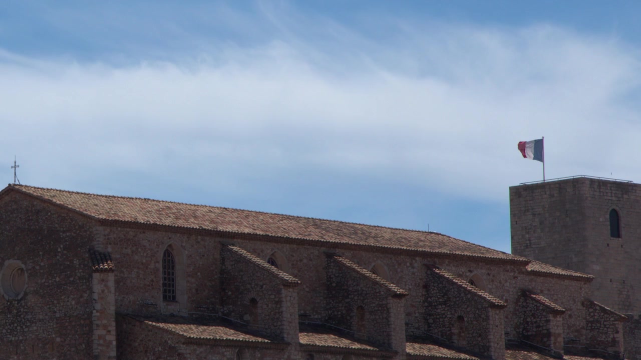 Ampia inquadratura fissa di una chiesa medievale in pietra e un campanile sotto cieli azzurri