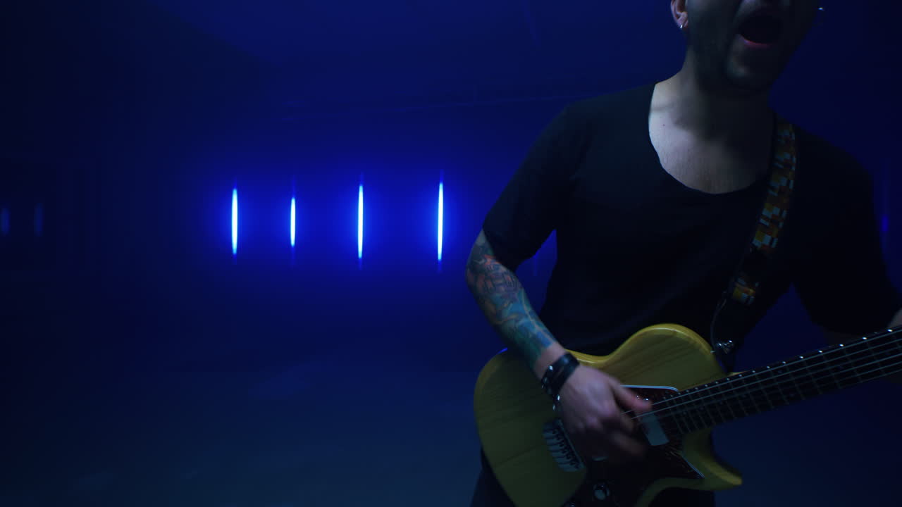 Man Playing Electric Guitar in Blue Studio