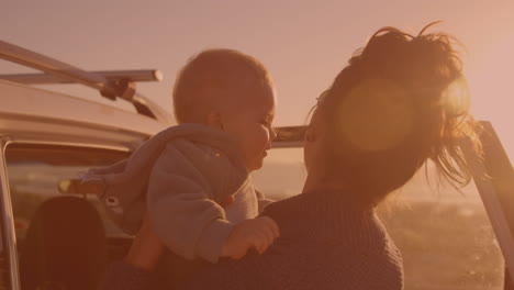 Happy-caucasian-woman-holding-a-baby-near-the-car-on-the-street