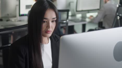 attractive young woman working on decktop computer while working in big open space office. portrait of positive business female looking at computer screen indoors