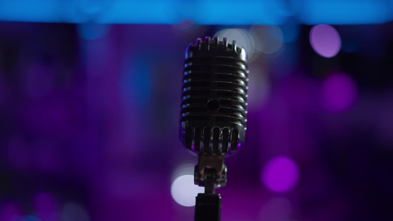 micrófono acústico de primer plano con luces de escenario apagadas en segundo plano. equipo de concierto profesional negro en la oscuridad después del final de la actuación en interiores. vida nocturna y entretenimiento.