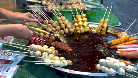 hands selecting skewers from a food stall