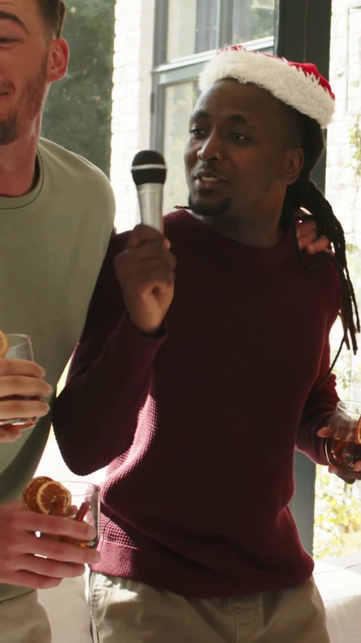 Vertical video: Singing Santa-hat man leading friends at home when music starts, passing mic
