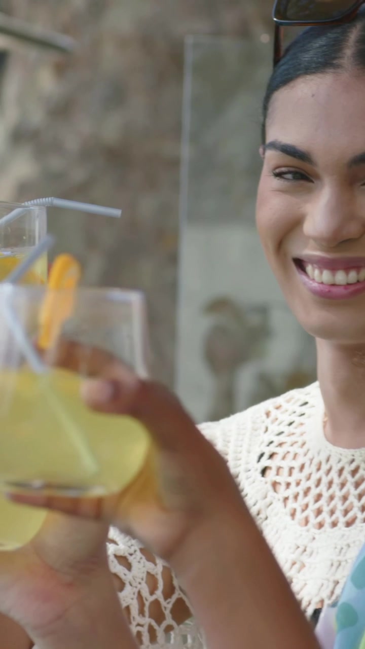 Donna che ride, offre un bicchiere da condividere sul patio, con un bagliore animato sul bicchiere per marketing