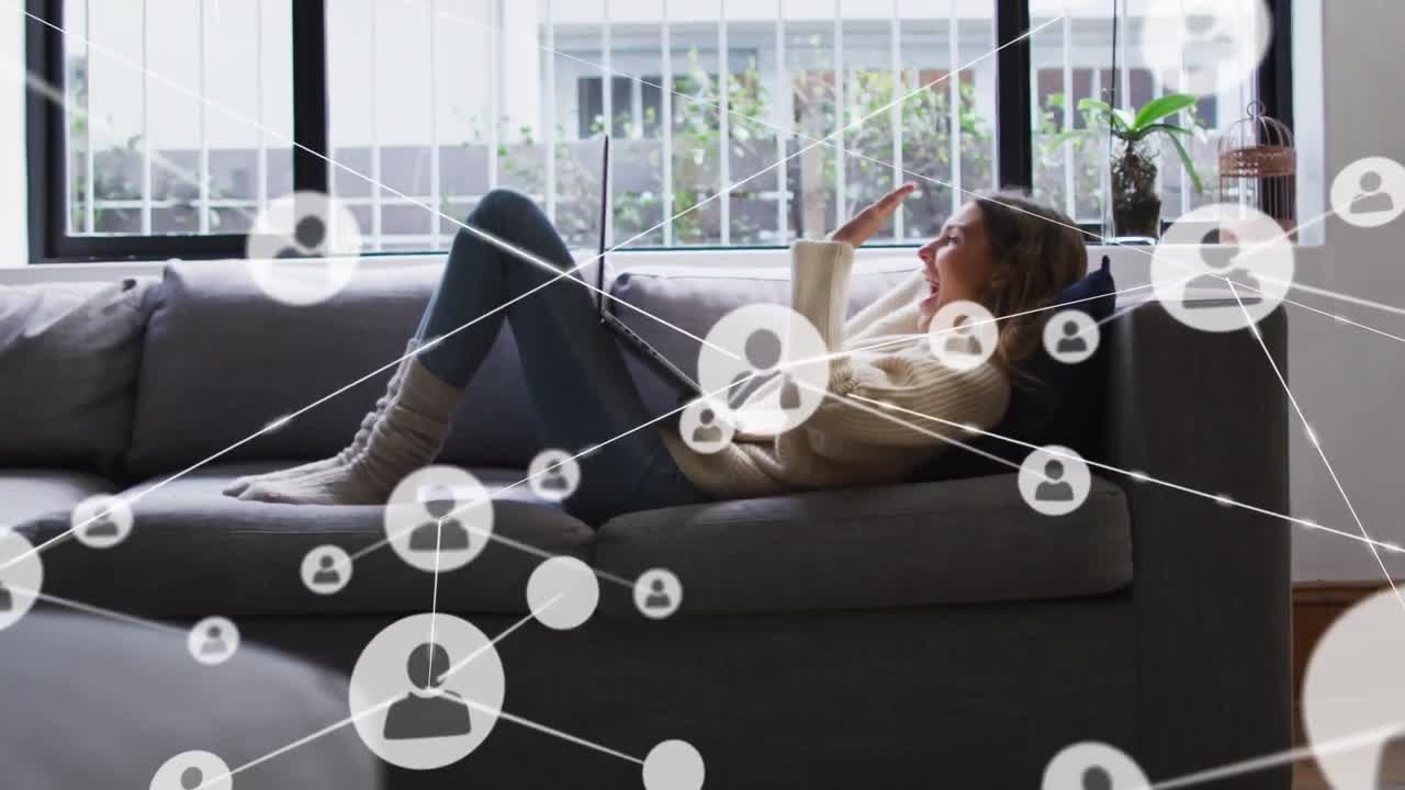 연결된 아이콘의 애니메이션, 코카시안 여성이 소파에 누워서 노트북을 사용하여 비디오 통화를하고 있습니다.