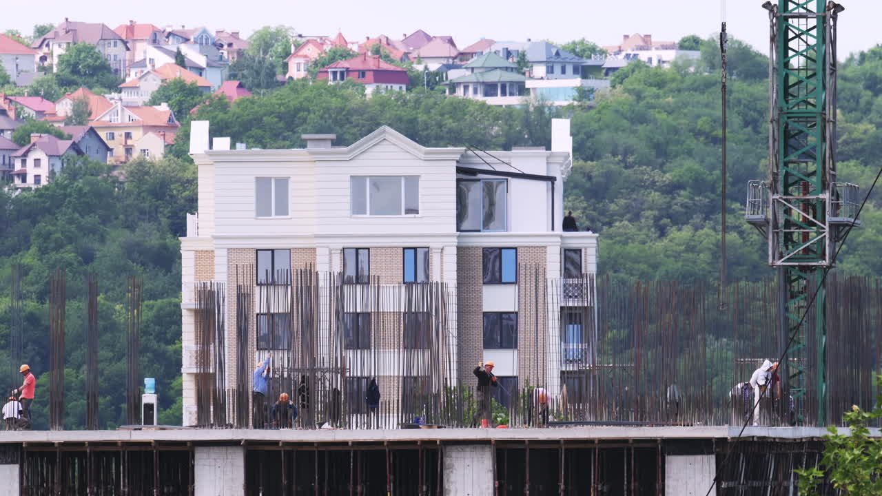 Time lapse of construction workers building a residential complex with cranes in the background