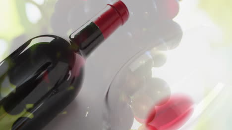 composite of glass with red wine over grapes background