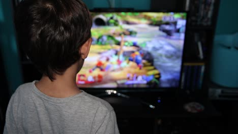 cabeza trasera de un niño no identificable mirando una pantalla mientras juega videojuegos electrónicos en un televisor lcd