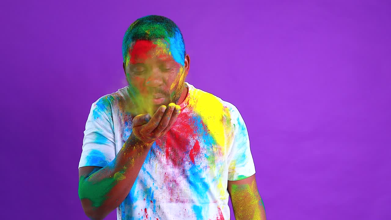 L'uomo afroamericano celebra il festival di holi sullo sfondo viola dello studio