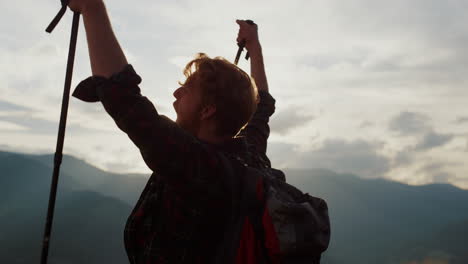 el excursionista eufórico celebra levantando las manos en las montañas. el tipo emocional en la cima