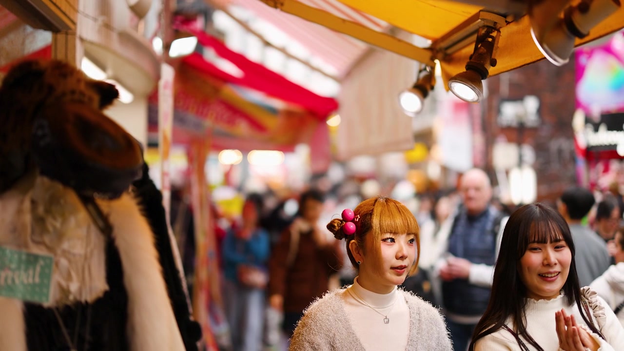 Giovani donne curiosano in un vivace mercato all'aperto in Takeshita Street, Tokyo, Giappone.