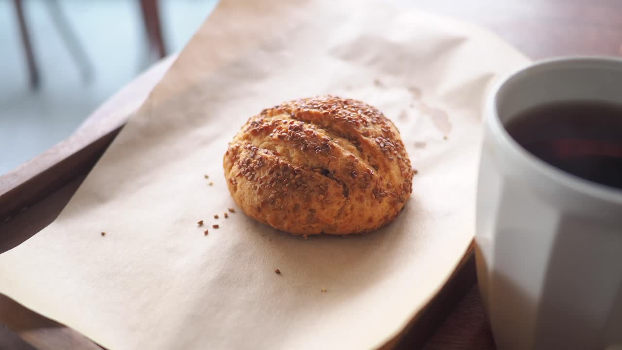 Hand Picking Up a Sesame Seed Pastry from a Wooden Tray