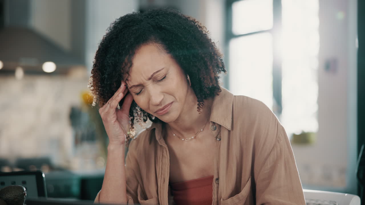 Stressed woman working from home at her kitchen table