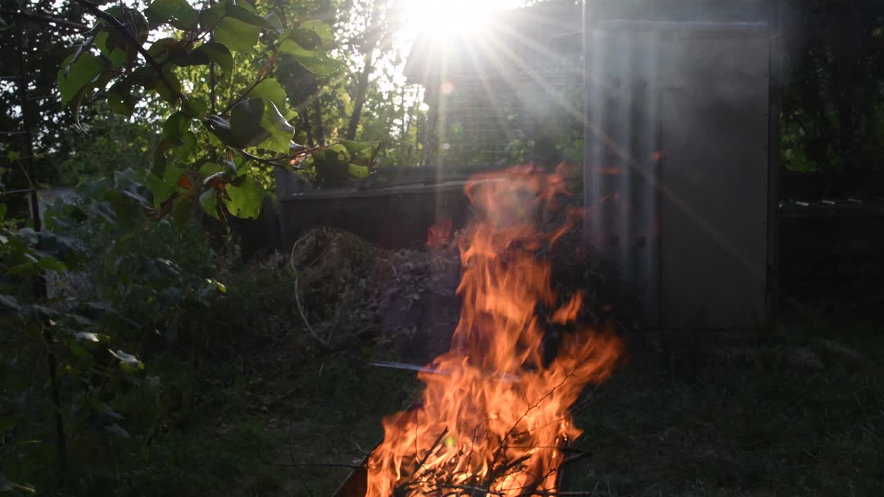 fuego ardiente borroso bajo los rayos del sol con llamarada de lente. llamas de fogata en un fondo rústico borroso