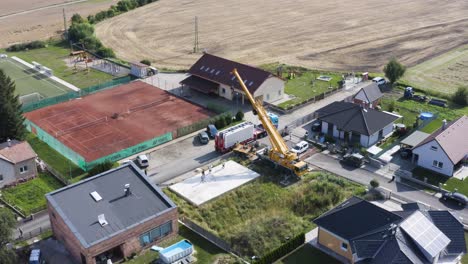 Mobile-crane-unloading-building-panel-from-truck-at-construction-site