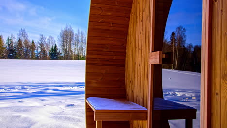 wooden sauna house on snow-covered field on a sunny day