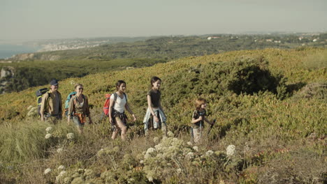 family with backpacks walking along hiking trail on a sunny day