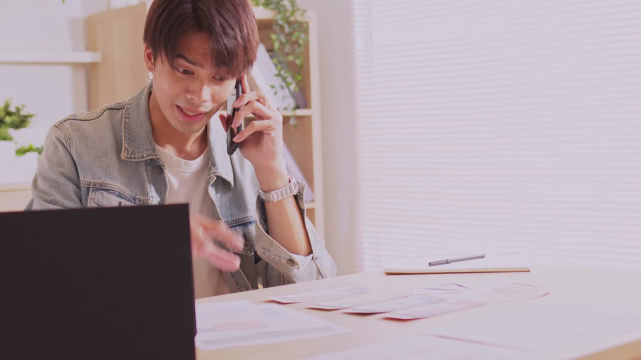 아시아인 디자이너는 스마트폰으로 커뮤니케이션을 하고, 프로젝트와 서류 작업을 하며, 노트북으로 책상에서 집에서 일합니다.