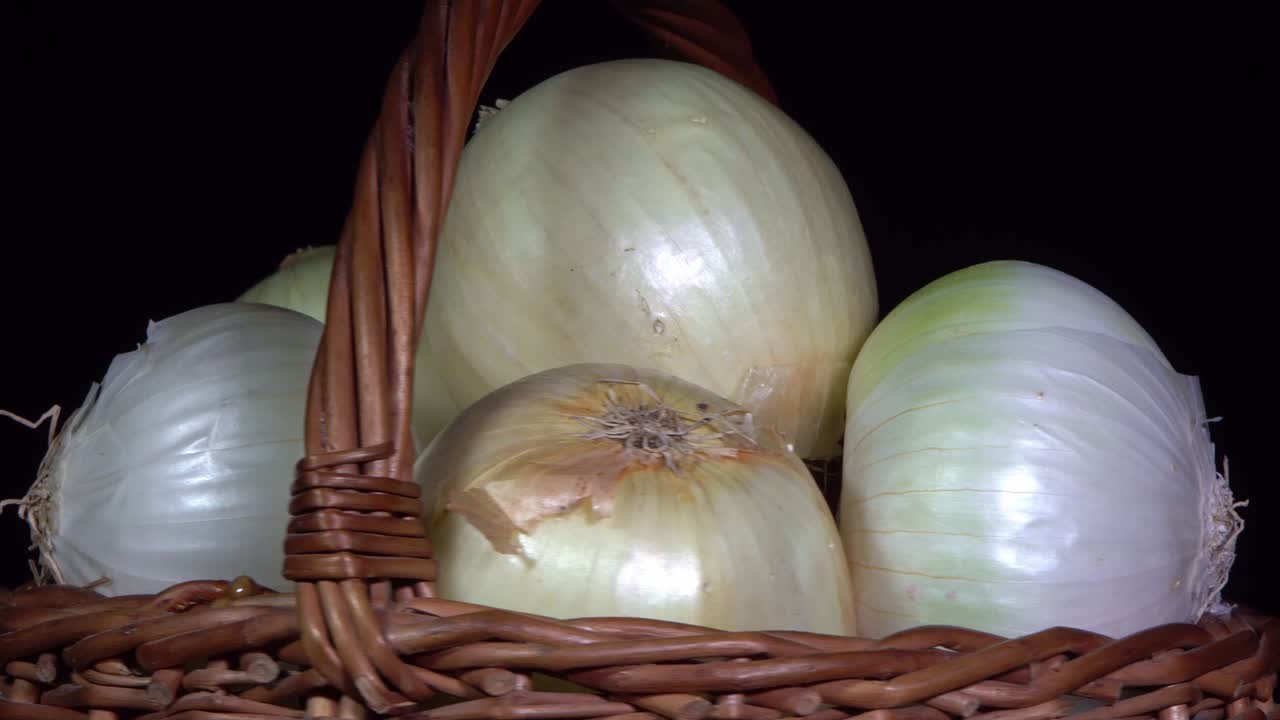 Vegetarian healthy food, composition of vegetables,  rotation of a basket with onions on a black background