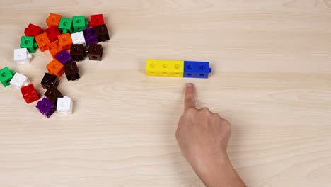 hand arranging colorful cubes on a table