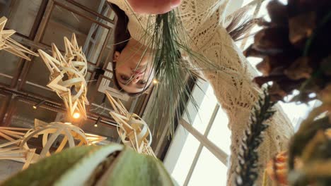 woman arranging a floral display in a cafe with unique decor.