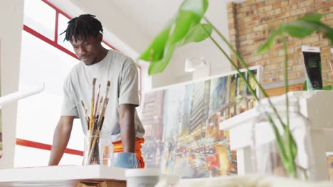 African-american-male-painter-holding-brush-and-thinking-in-artist-studio