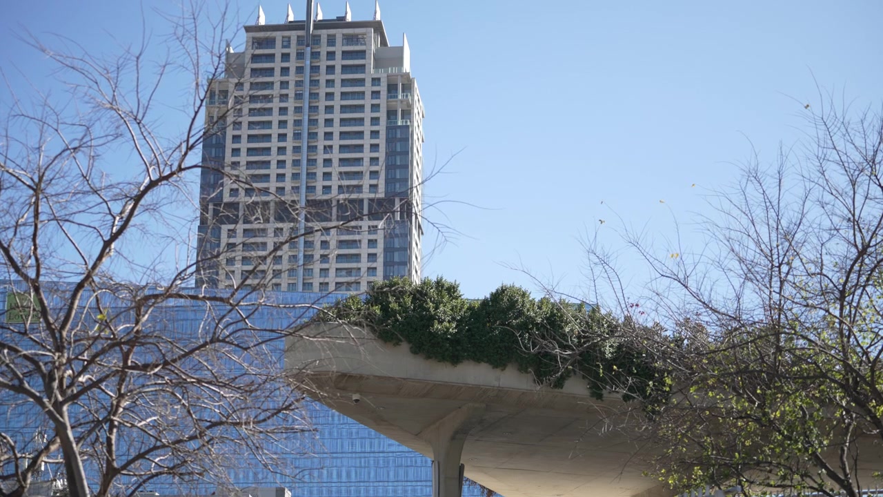 Un imponente rascacielos se eleva detrás de una plataforma única cubierta de vegetación en Sandton. Ideal para temas de arquitectura y desarrollo urbano.
