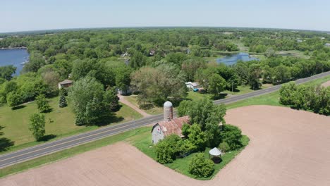 aerial reverse pullback wide shot of an old barn and silo in the rural farmland of minnesota