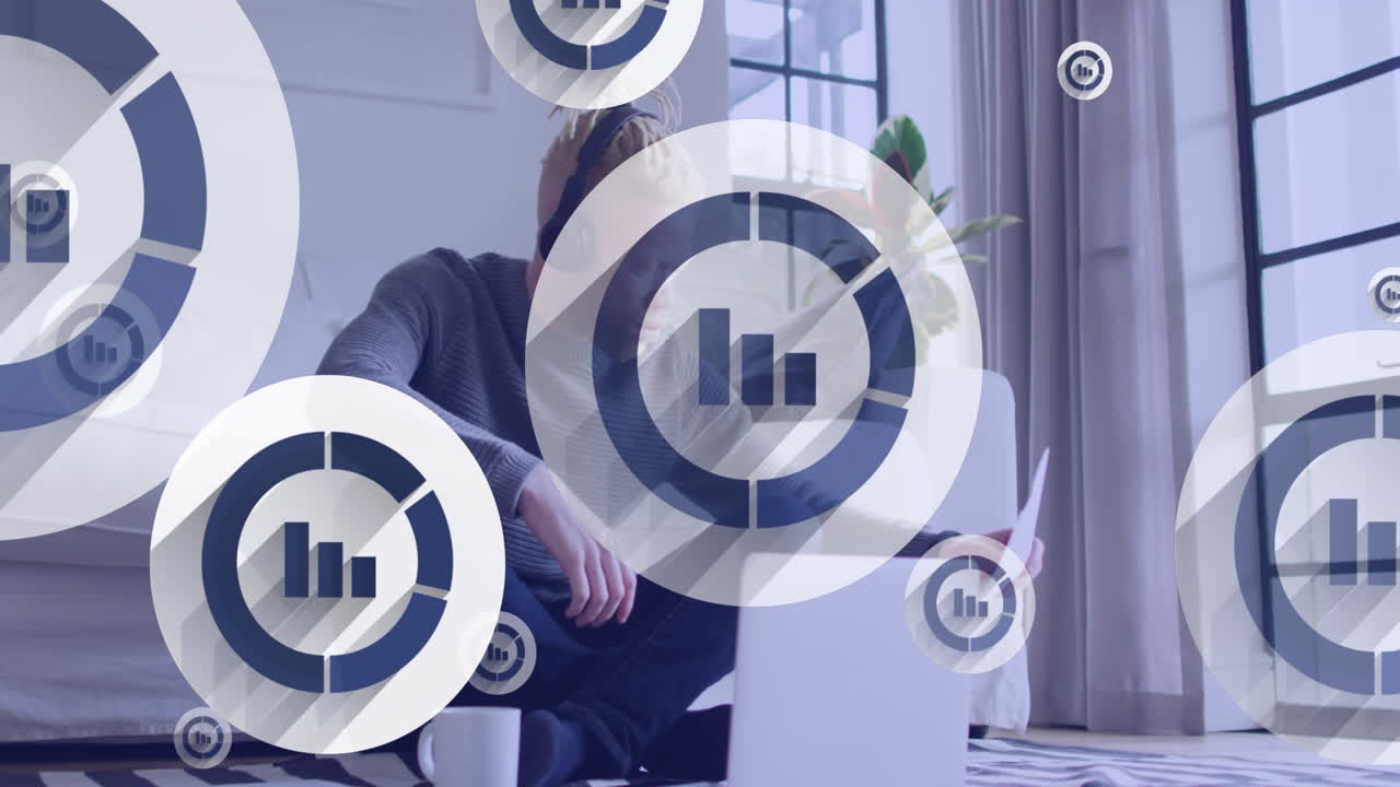 animación de iconos estadísticos flotando sobre un hombre albino afroamericano que trabaja en una computadora portátil en casa