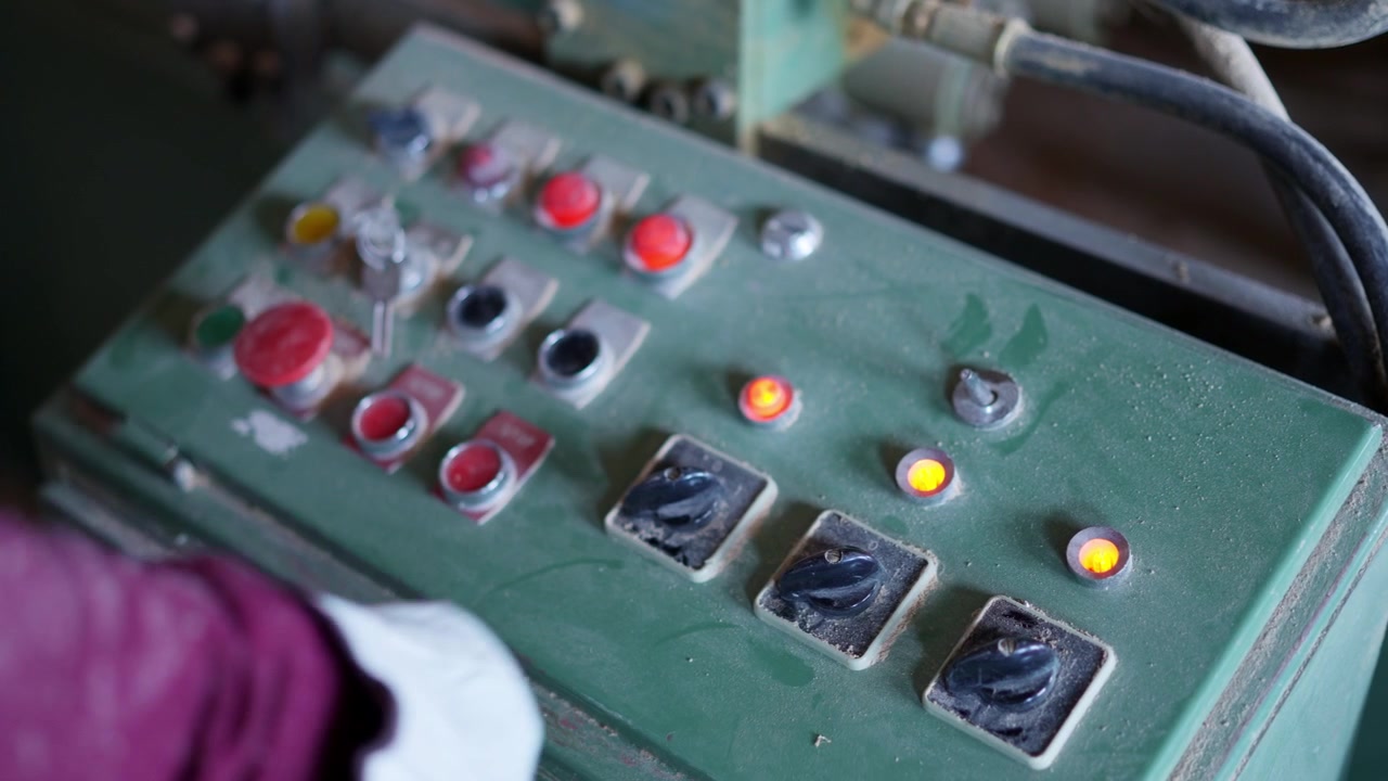 Worker hand turning on industrial machinery control panel