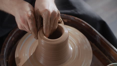 manos moldeando arcilla en una rueda de cerámica