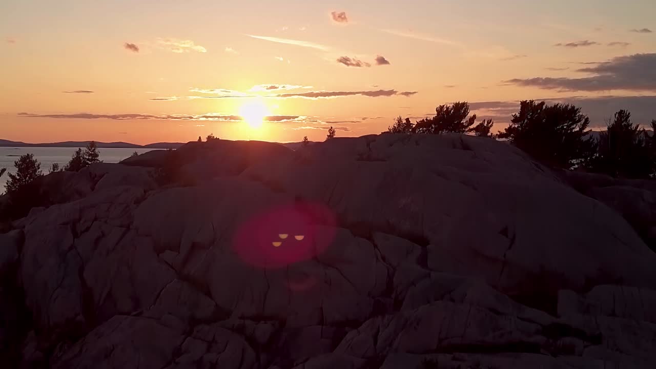 Inukshuk em Ilha Rochosa com Pinheiros ao Pôr do Sol, Drone Aéreo Amplo com Pedestal Ascendente
