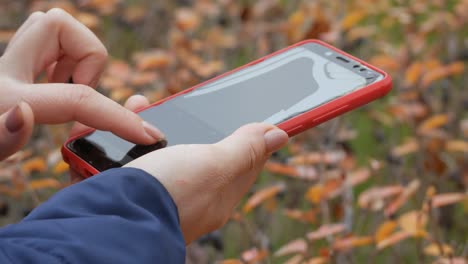 broken red phone screen. close up of woman's hand touching red mobile phone with blurred yellow green background, by sending sms messages.