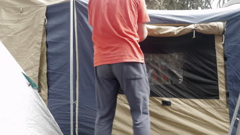 man unrolling or closing canvas tent windows in the afternoon