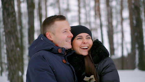 Primer-Plano-De-Un-Hombre-Y-Una-Mujer-Enamorados-Parados-En-El-Bosque-Invernal-Abrazándose-Y-Mirando-A-Lo-Lejos