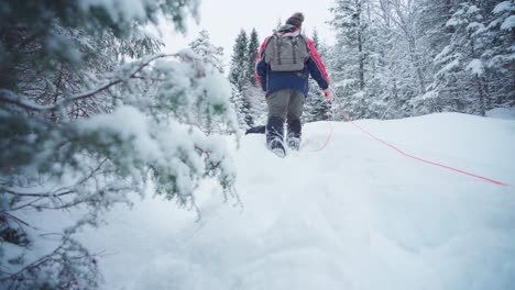 ground level shot of a man walking through deep snow in the forest on a cold winter day in norway