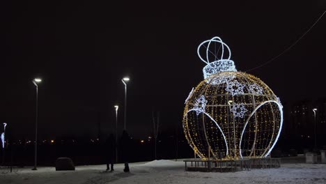 giant illuminated christmas ornament in city park at night