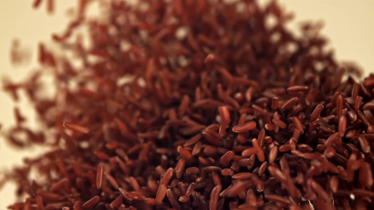 Red Rice Grains Falling and Piling Up in Slow Motion