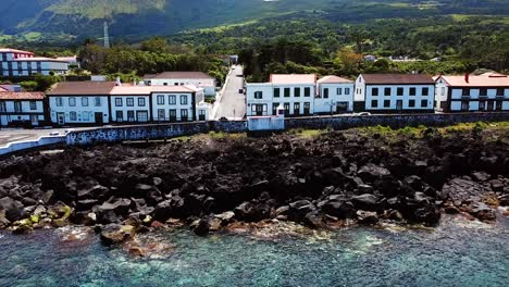 toma deslizante de la costa rocosa azulada y los edificios de sao roque do pico en la isla pico, azores