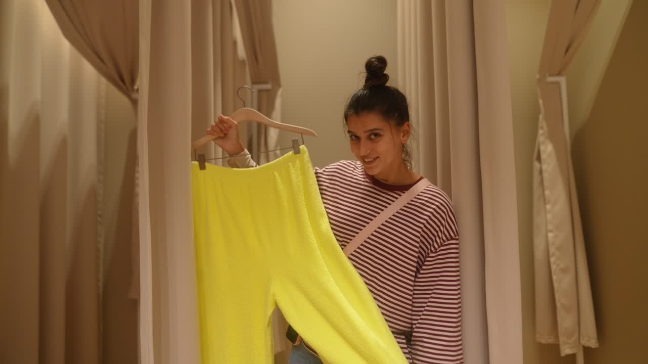 Young Woman Trying on Yellow Pants in a Fitting Room