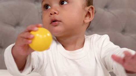 cute baby playing with ball on bed