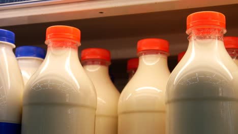 close-up of many beautiful milk bottles with red caps and a male customer's hand takes one