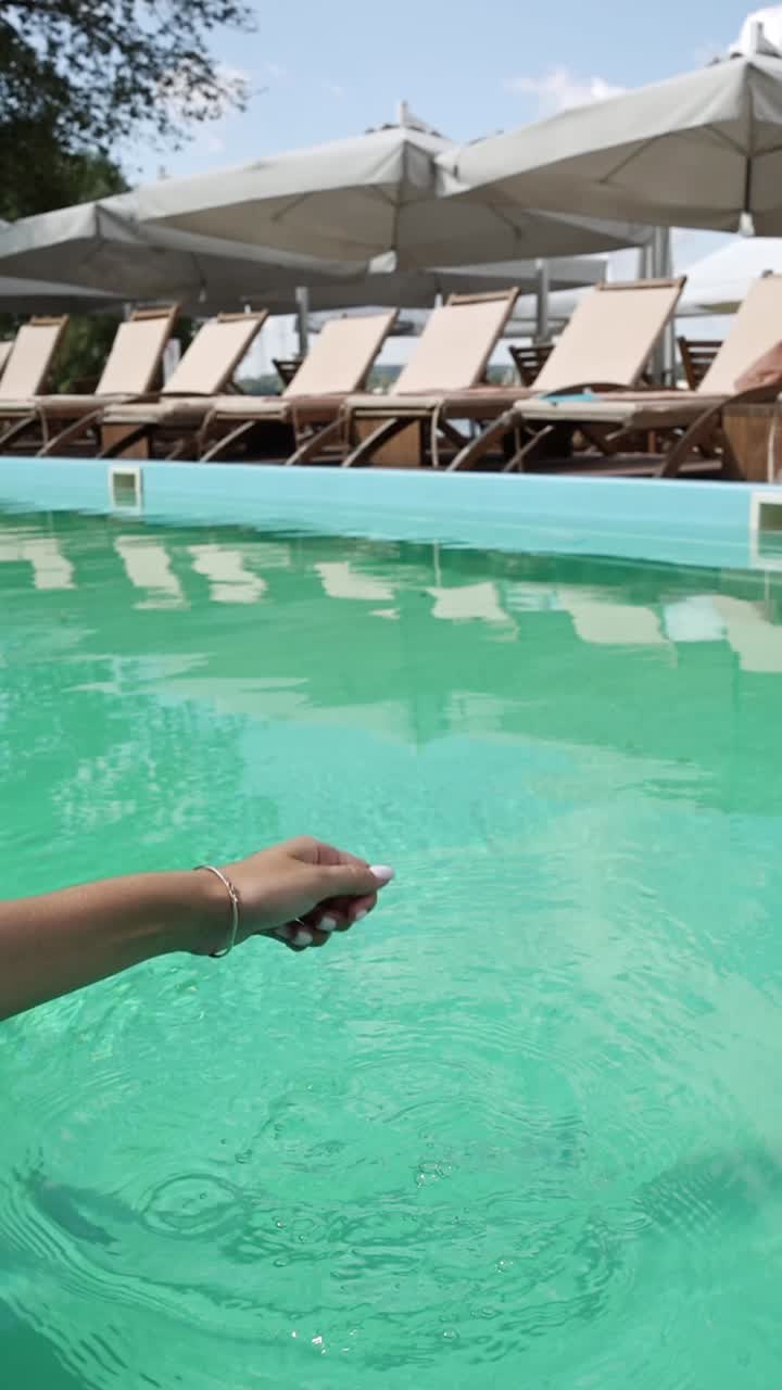 mujer salpicando agua en una piscina de un complejo