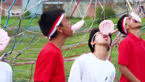 group of young indonesian men with headbands intensely participate in traditional cracker eating race