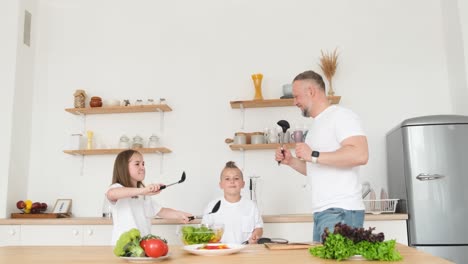 dad dances with children while cooking food at home in the kitchen a happy family vegetarian food dad dances with children while cooking food at home in the kitchen a happy family vegetarian healthy food